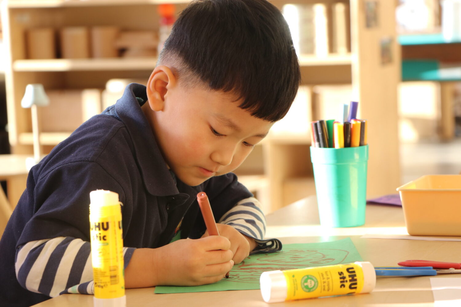 Nursery pupil at desks working and doing art.