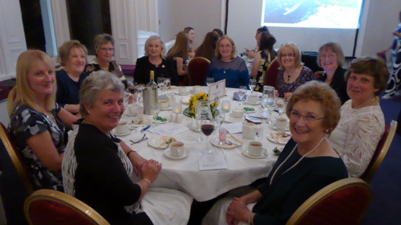 ALUMNI Old Girls. Associates of the school at a event, seated around a table having drinks and talking.