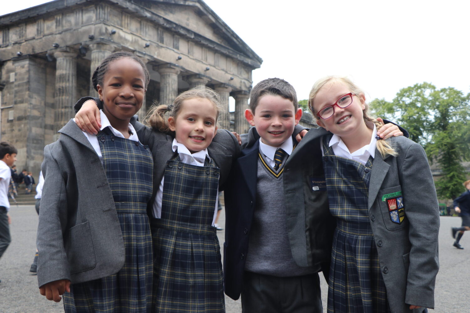 Junior pupils outside front the school having group photo looking cheerful together on school playground.