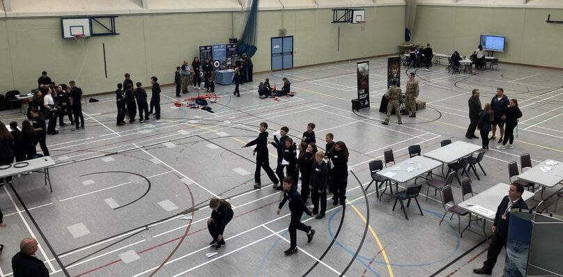 Careers Taking Off featured. Pupils and career advisers in sports hall holding talks and information at career stands.