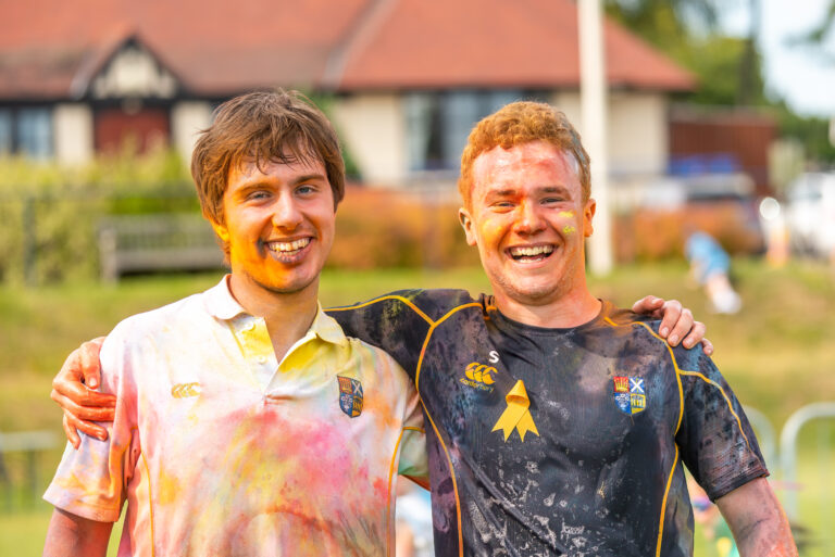 HSD Colour Run 2. Pupils looking happy and cheerful, arm on each other shoulder covered in gulal powder.
