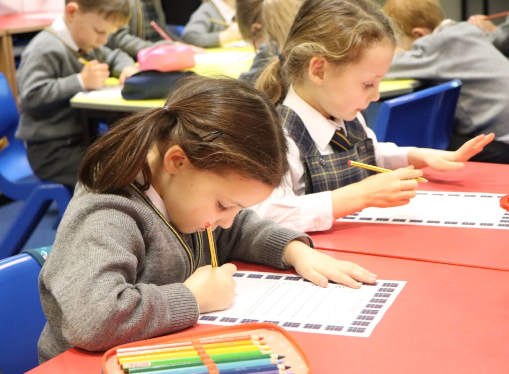 JY working away . Junior pupils at desks working and writing.