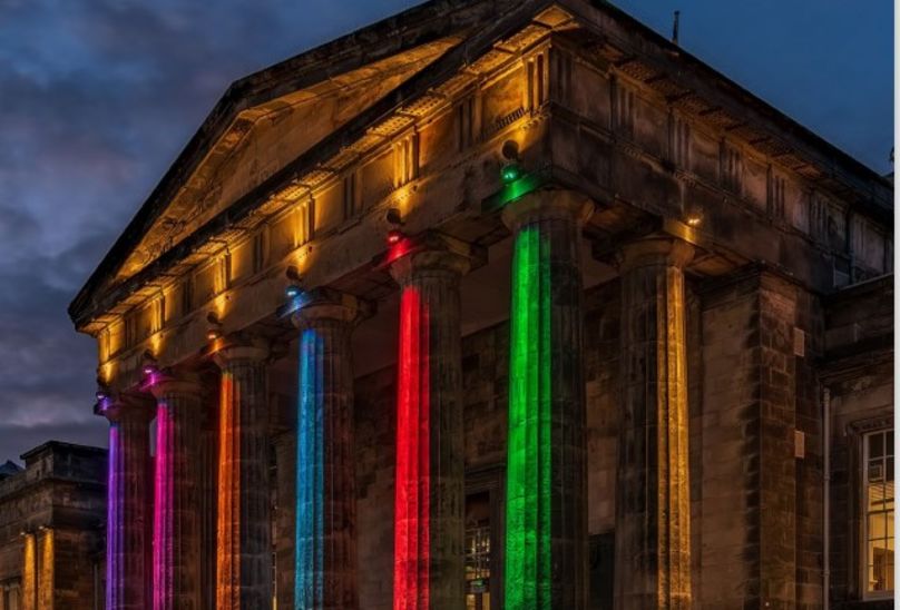 New Edition Of Schola Clara Available Now Front of Dundee school lit up with multi coloured lights.