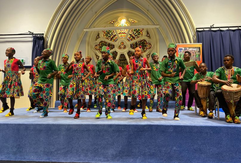 Singing Children Of Africa At HSD. Children on stage dancing in African inspired clothing with percussion band playing alongside by them.