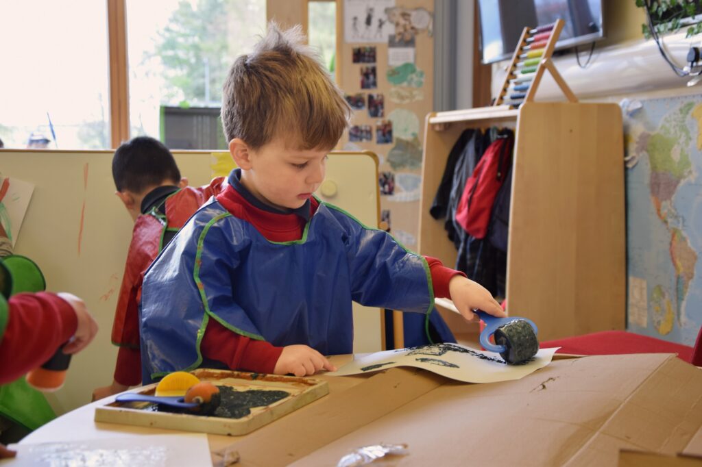 Nursery child rolling paint onto paper in the Nursery