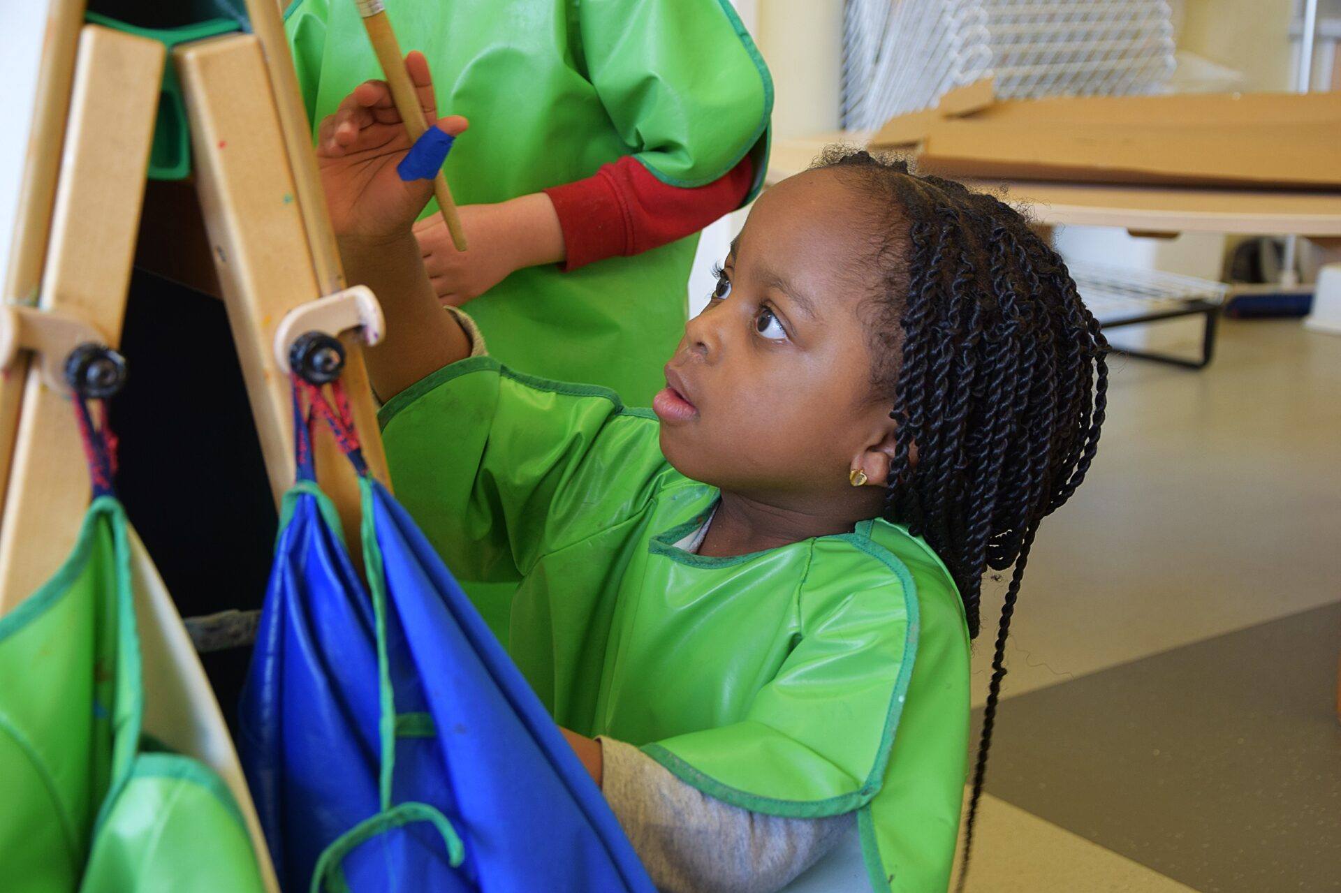 Nursery girl paints with green apron on