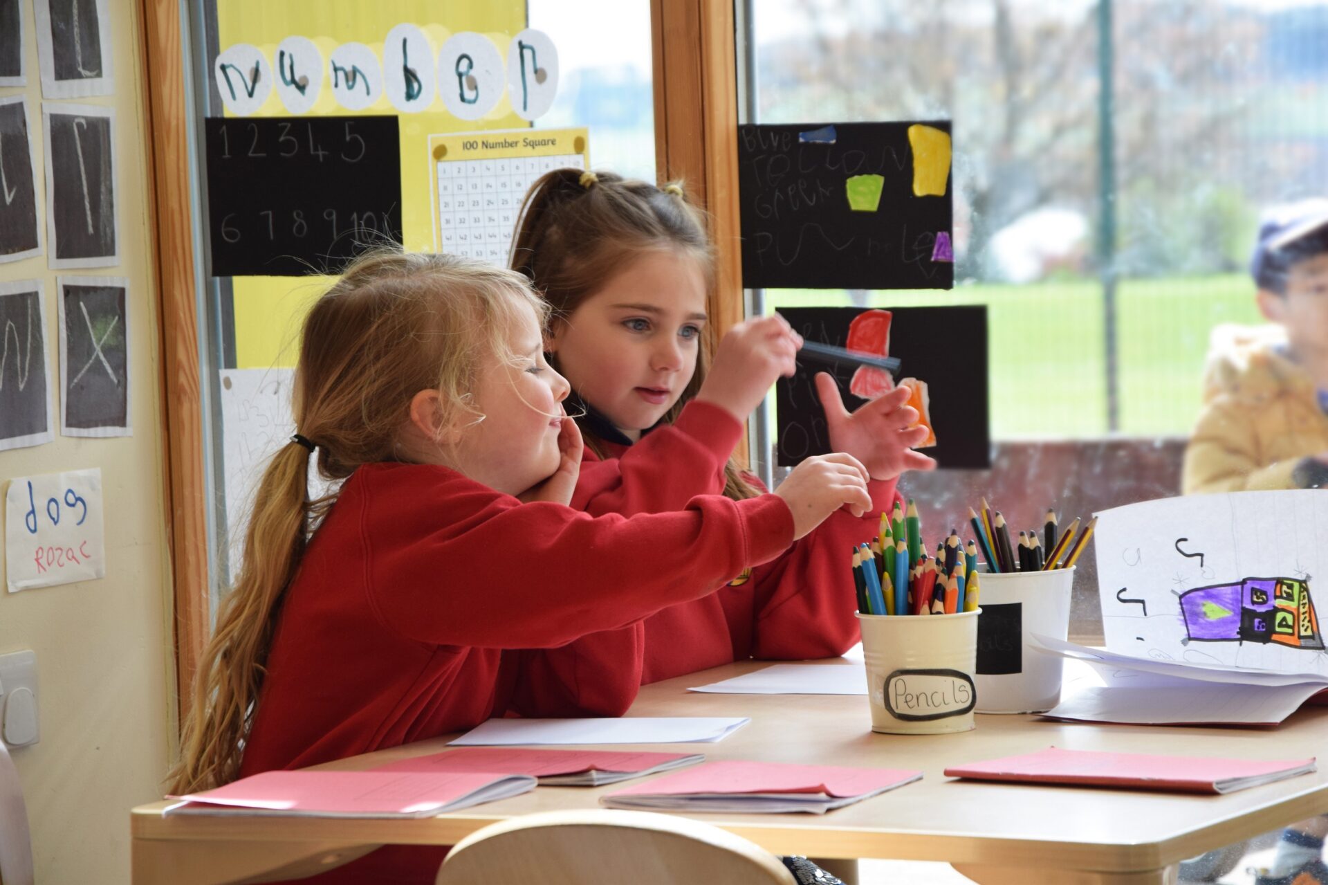 Two nursery pupils side by side having fun as they draw