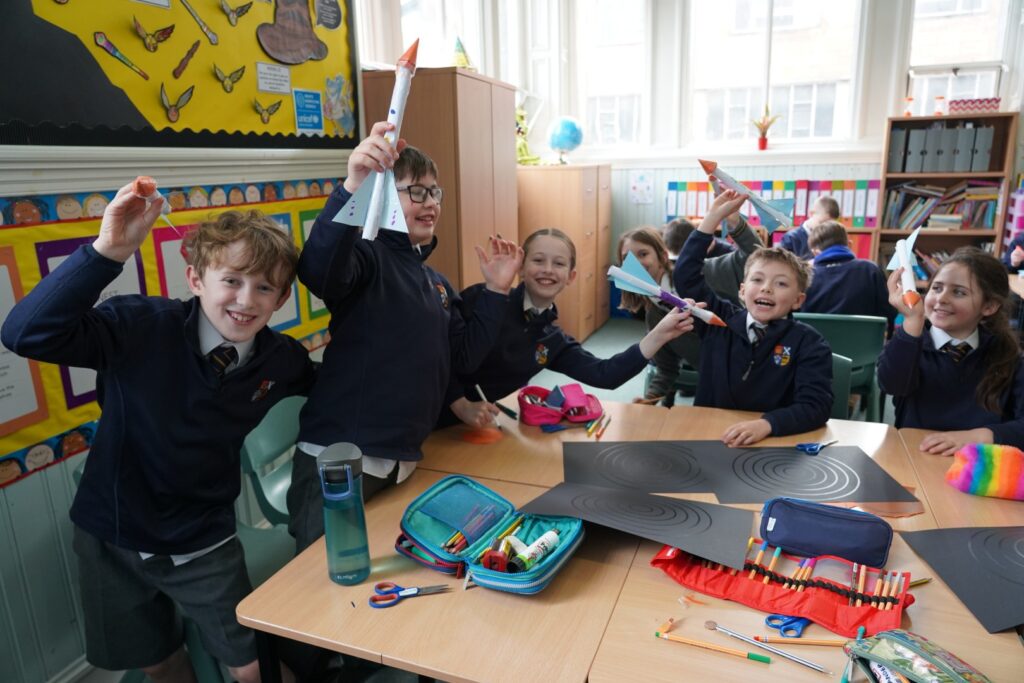 L5 pupils smile and hold the rockets which they built as part of Space Day