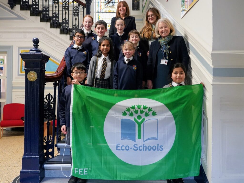 Members of he Eco Club and Mrs Rose and Mrs Hudson on the Margaret Harris stairs holding the Green Flag